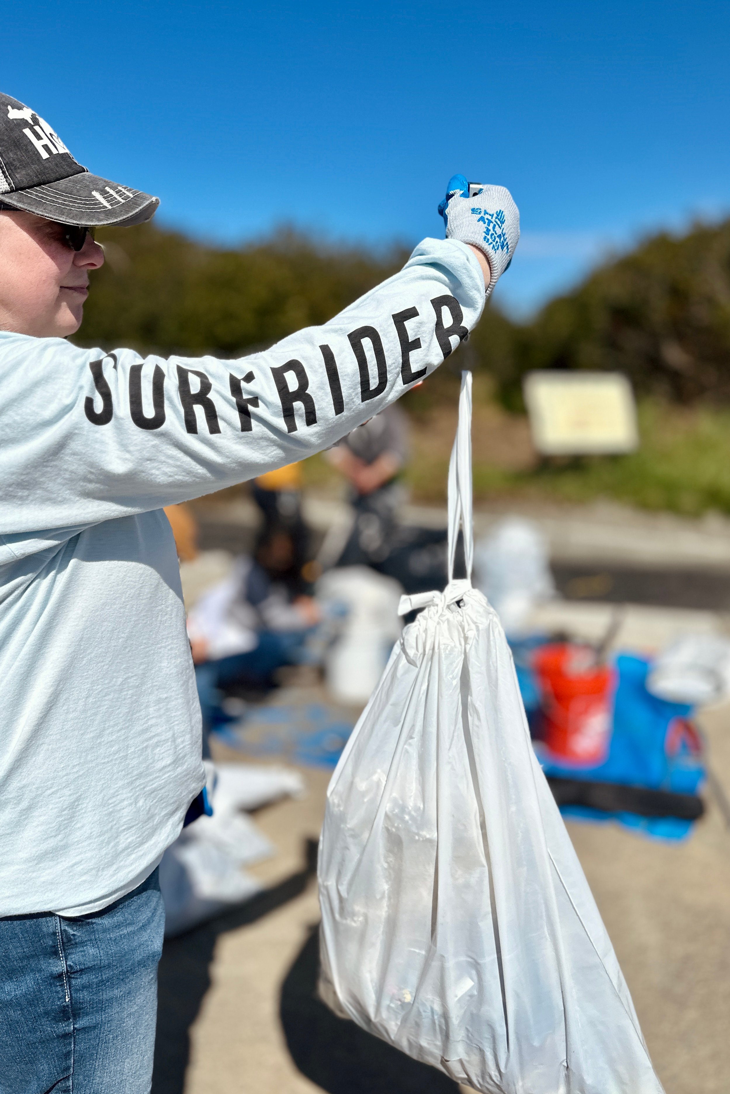 A volunteer holds up a bag full of trash to weigh as part of the data collection effort 