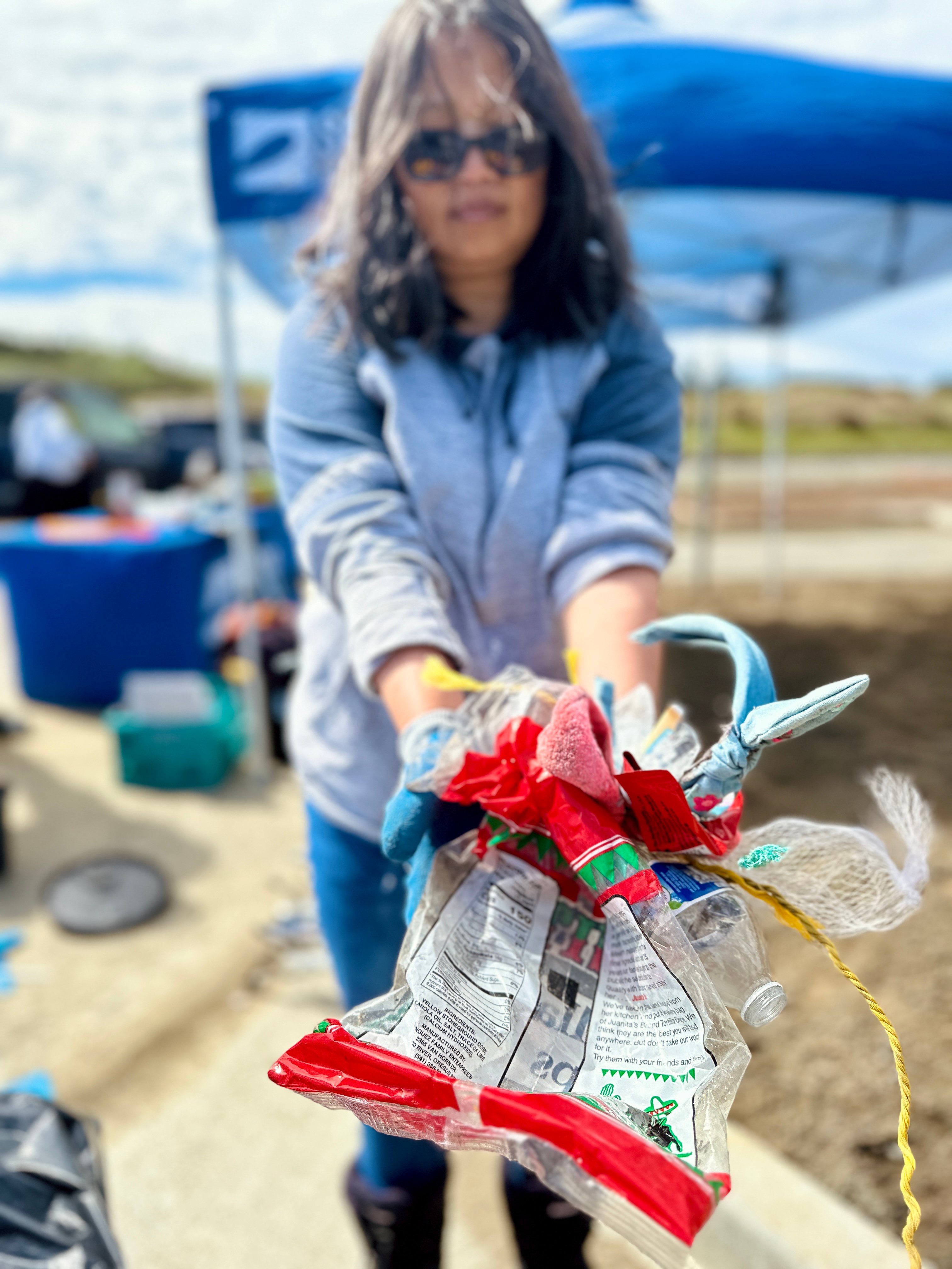 A volunteer holds up a handful of trash from a beach cleanup