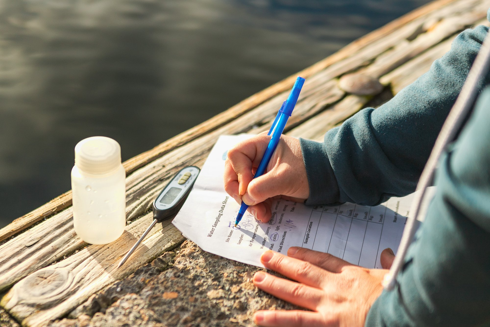 A close view of a volunteer collecting, testing, and recording data of water testing location 